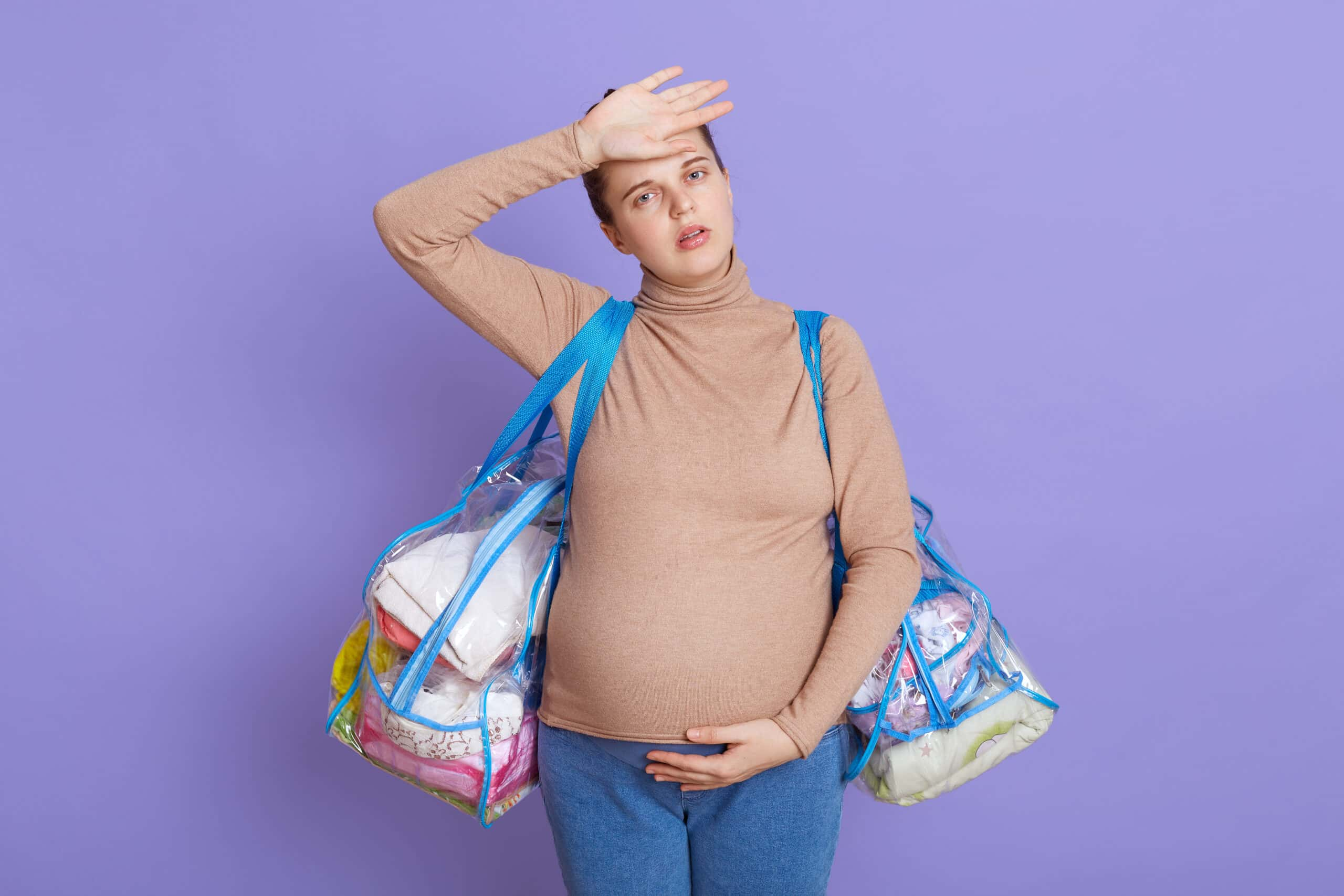 caucasian young beautiful pregnant tired future mom feeling fatigue headache looks tired exhausted touching her forehead holding two bags going maternity house scaled Fatih